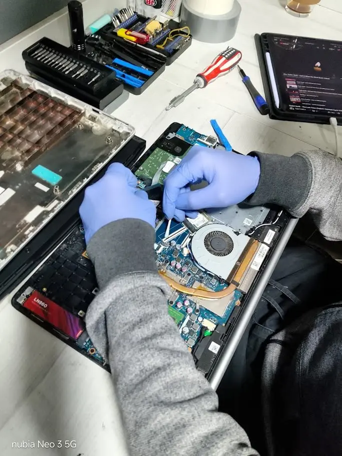 Técnico de El de Soporte limpiando la placa de un portátil mojado en Cali