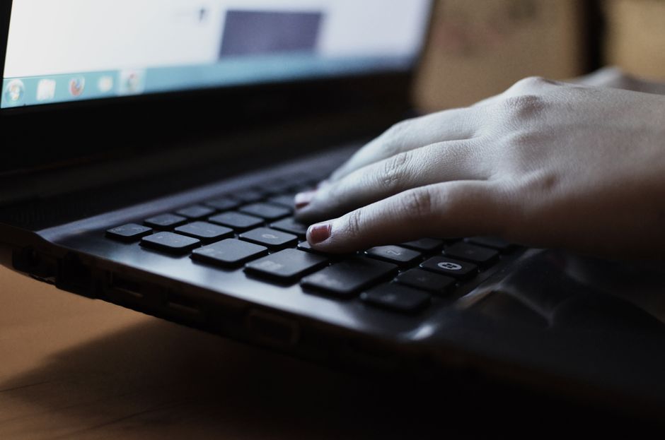Persona escribiendo en el teclado de un portátil con la pantalla encendida, ilustrando una revisión de pantalla