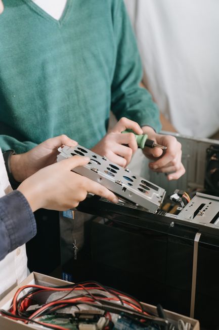 Técnico reparando la tarjeta madre de un computador portátil viejo en un taller